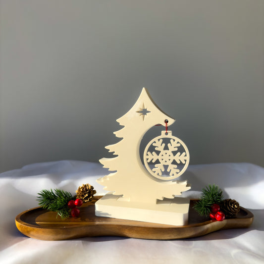 Minimalistyczny stroik świąteczny z gipsu polimerowego w formie kremowej choinki z zawieszką-śnieżynką, ustawiony na drewnianej podstawie.