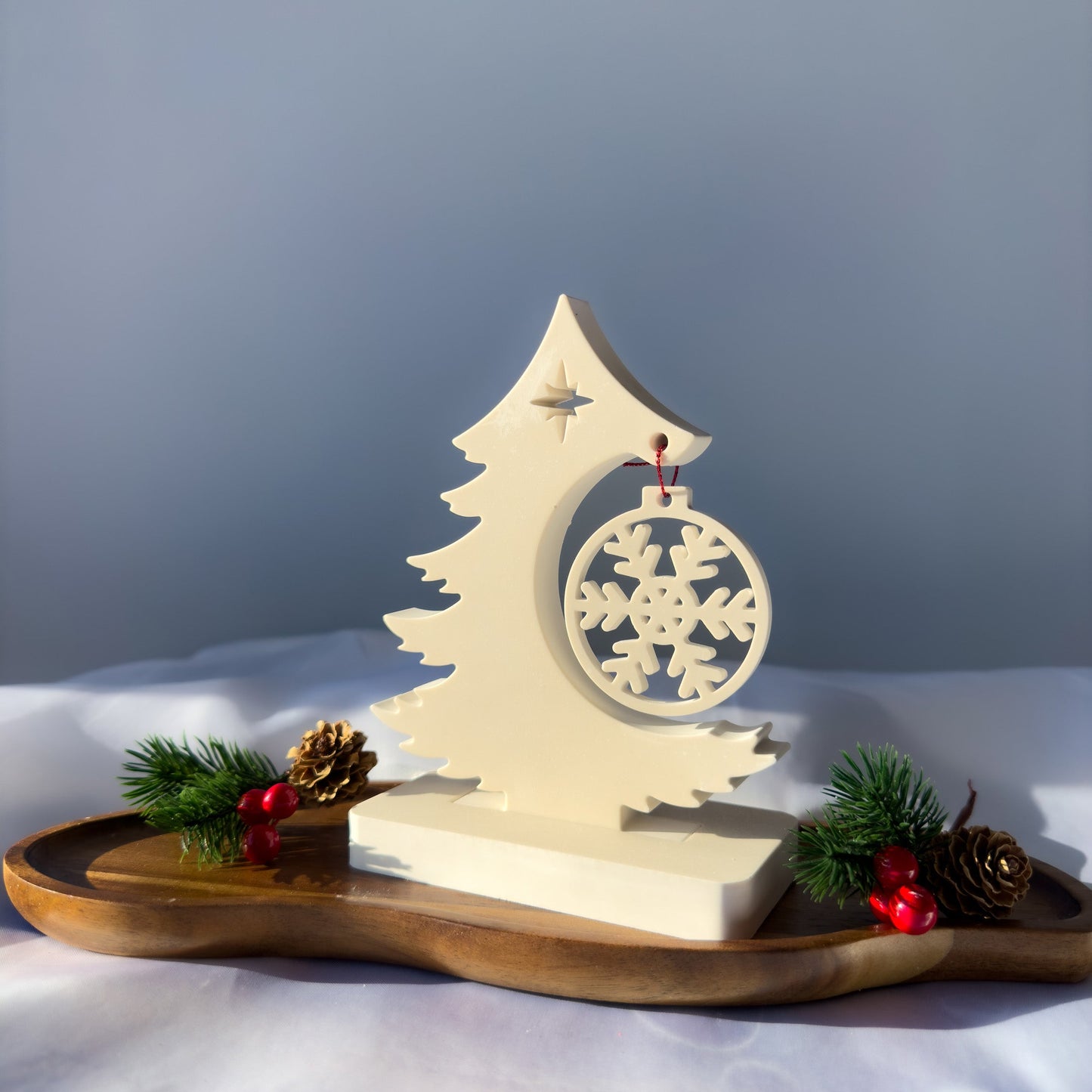 Minimalistyczny stroik świąteczny z gipsu polimerowego w formie kremowej choinki z zawieszką-śnieżynką, ustawiony na drewnianej podstawie.
