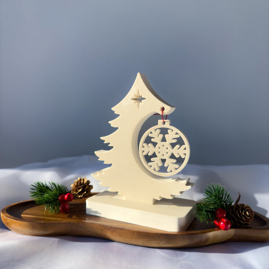 Minimalistyczny stroik świąteczny z gipsu polimerowego w formie kremowej choinki z zawieszką-śnieżynką, ustawiony na drewnianej podstawie.